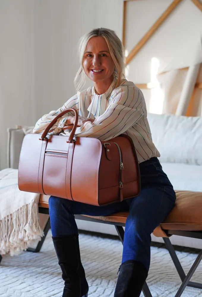 Michelle seated with a Carl Friedrik leather weekend bag