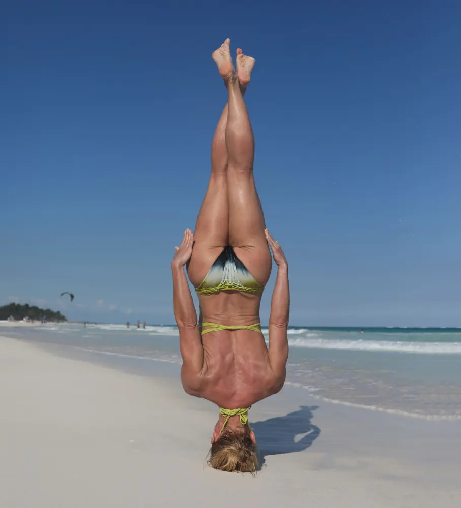 Michelle in a headstand on a white-sand beach